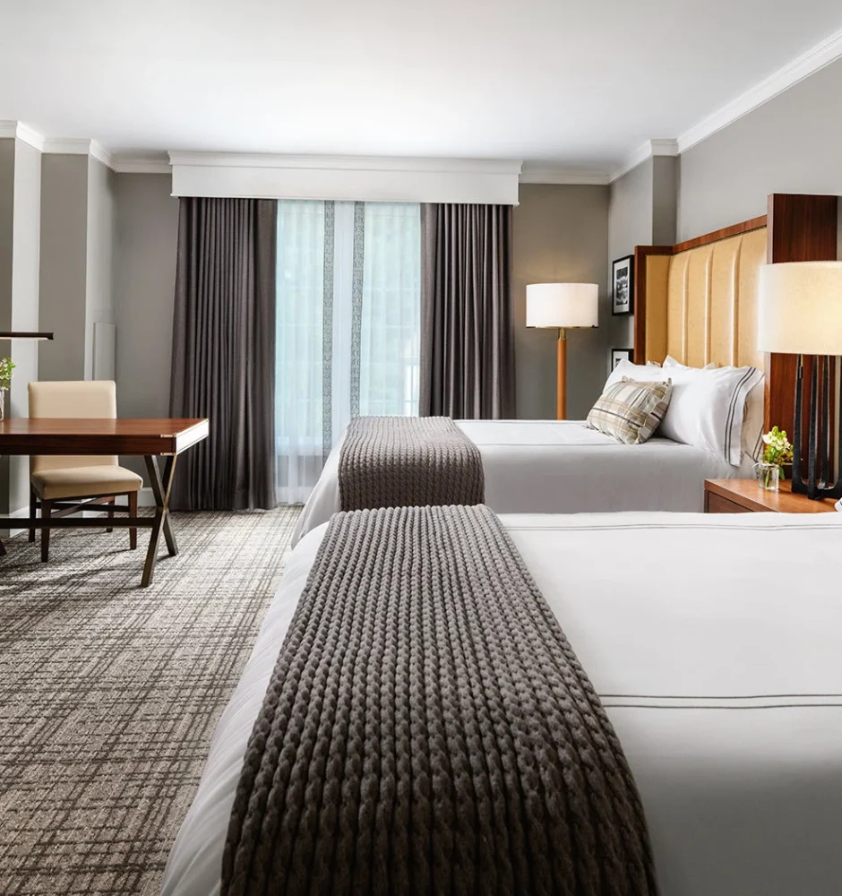 A hotel room with two beds, a desk, and a dresser.