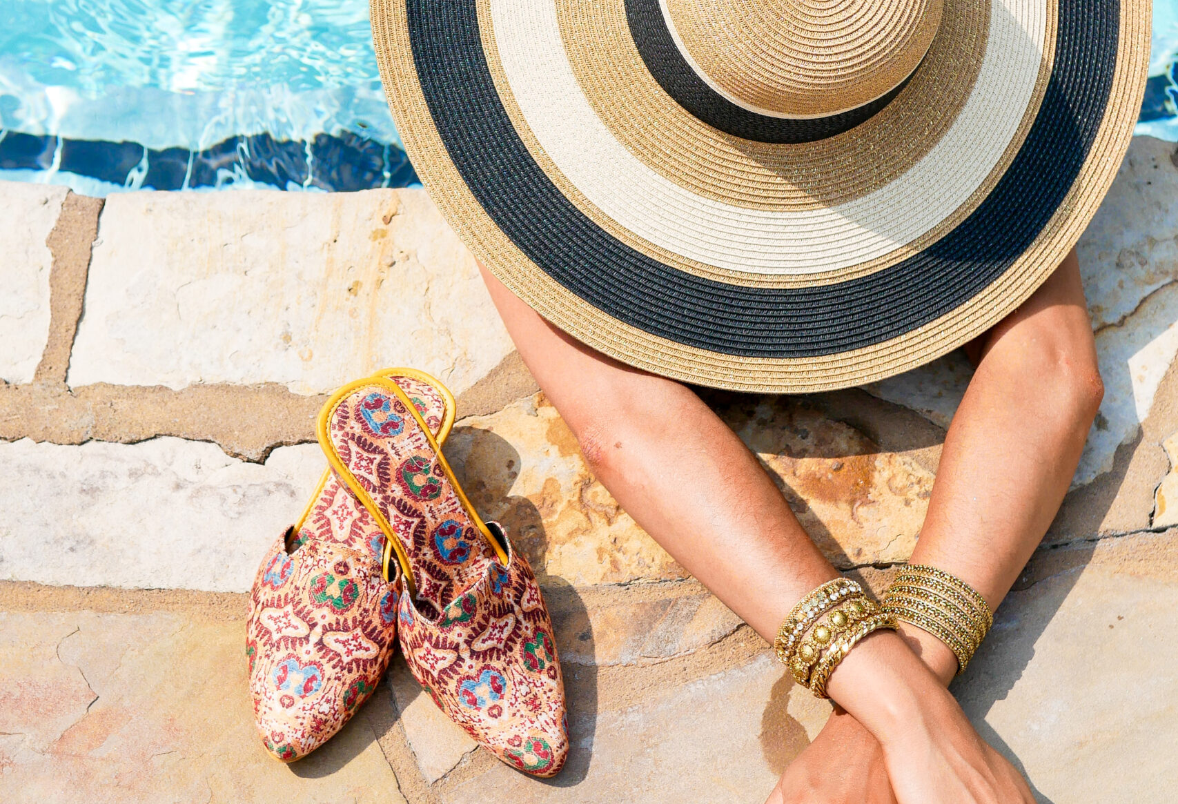 Woman in wide-brim hat relaxing at poolside