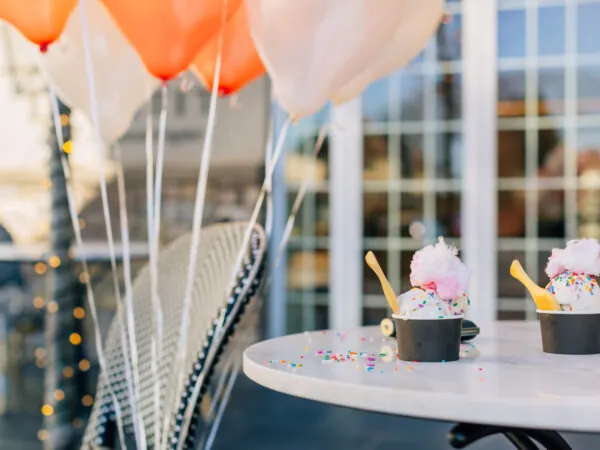 A small cake on a table is surrounded by balloons.