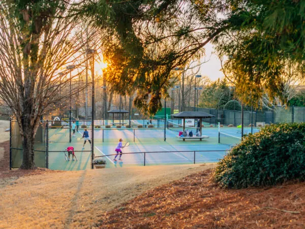 People playing tennis on outdoor courts at sunset