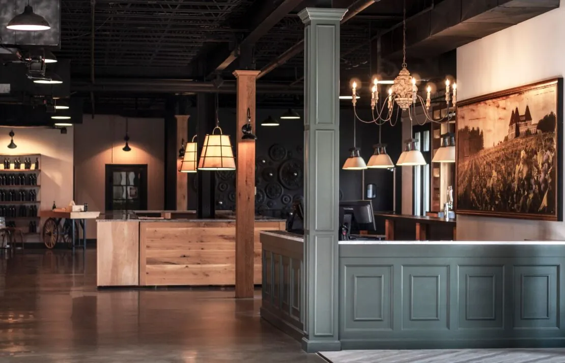Stylish winery tasting room with wooden bar, chandeliers, and modern decor.