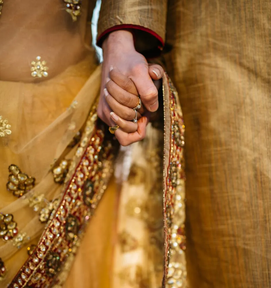 Close-up of couple holding hands in traditional attire