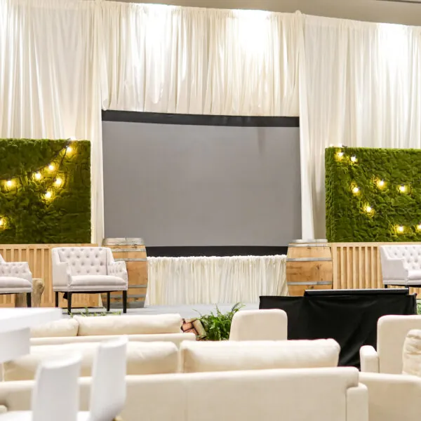 A stage set up with a large screen and chairs in front of a white curtain.