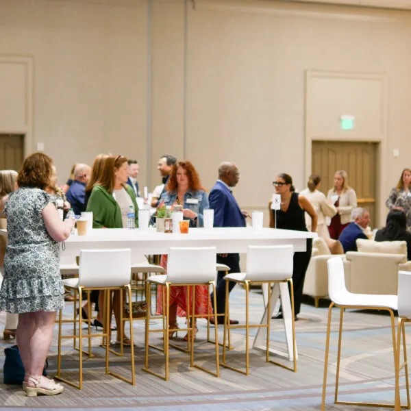 Guests standing and talking at high tables indoors