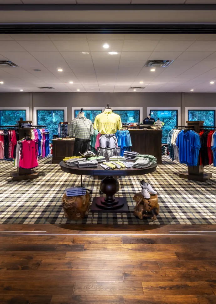 An open doorway leads to a bright, well-stocked retail store with various colorful clothes on display.