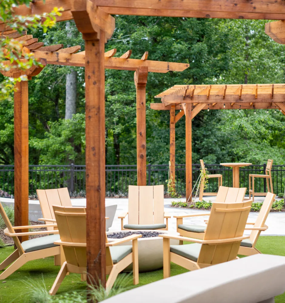An outdoor patio area with a wooden pergola and chairs.
