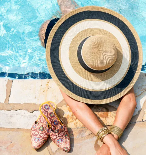 Woman in wide-brim hat relaxing at poolside