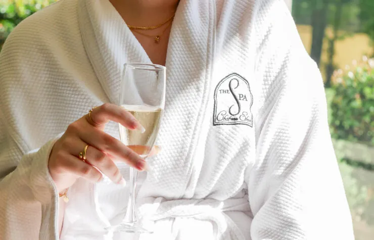 Woman in spa robe holding a glass of champagne