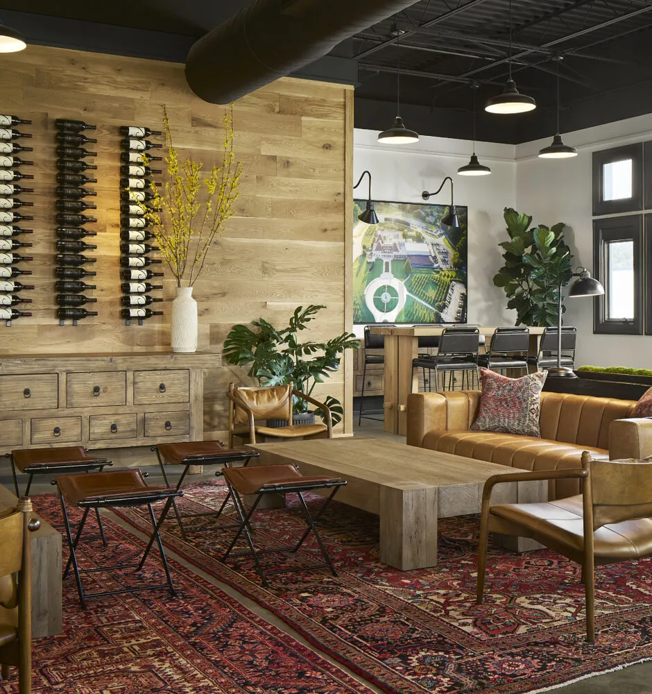 Modern lounge with leather couches, a wine rack, and a rustic wood wall.
