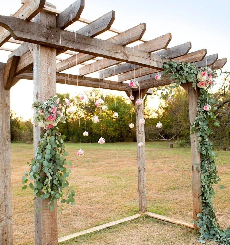 Rustic wooden arch decorated with flowers and greenery.